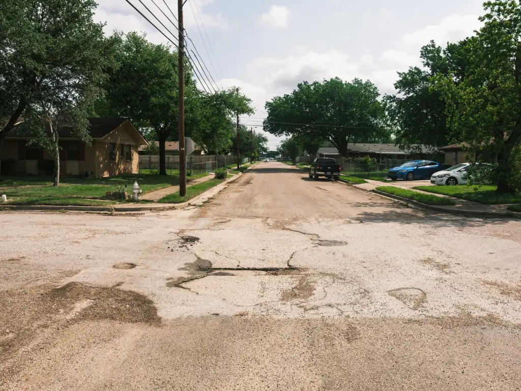 A view down Avenue B at its intersection with South Barbara Street shows the contrast of before and after. Avenue B was rehabilitated last year using the city’s “zipper” recycling machine, while South Barbara Street, seen at center, awaits its fix.