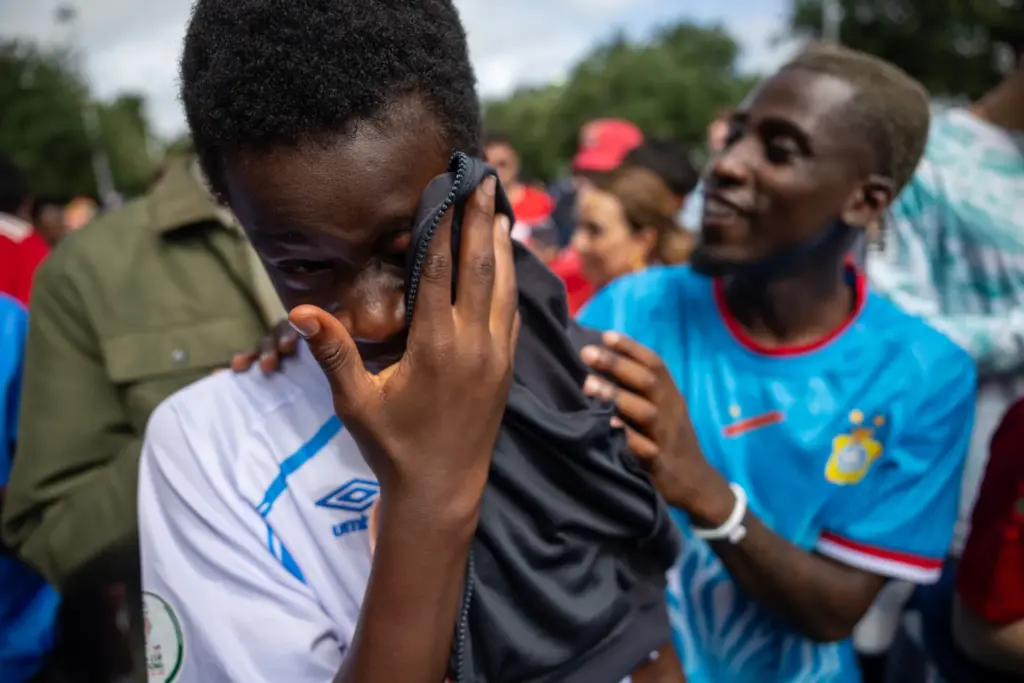 Kenasi Mwami, left, wipes away happy tears of as Patricque Kisindja comforts him while waiting in line to watch DR Congo face Portugal during the World Cup in June.