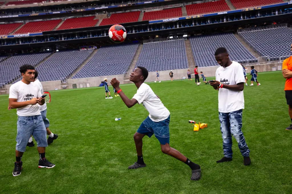 Kenasi Mwami, center, and the rest of the Houston reVision team play juggle a soccer ball until only one player is left.
