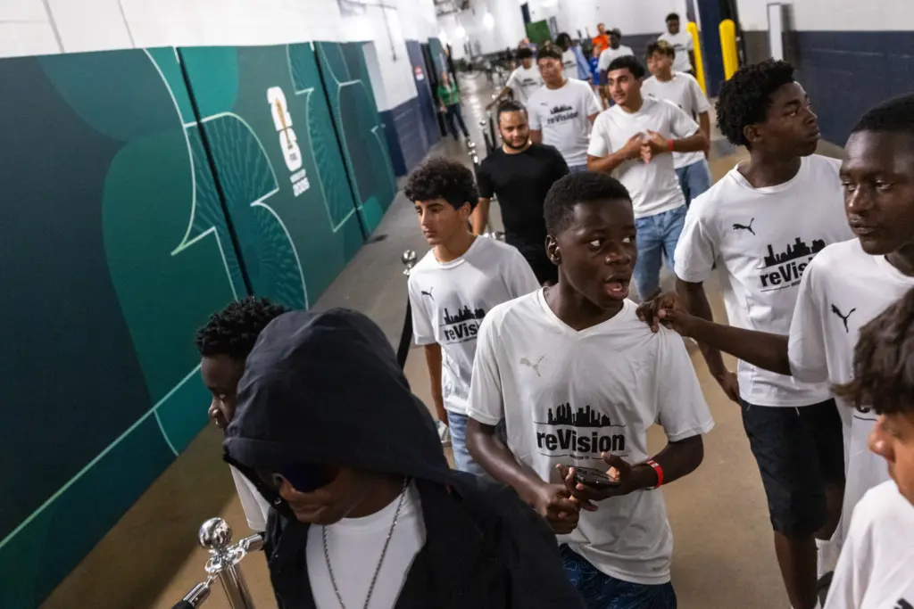 Kenasi Mwami, center, and members of the reVision team, reacts as he walks through the same hallways that World Cup players walked days earlier at NRG Stadium in Houston.