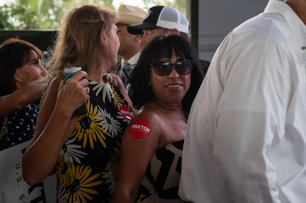 Lupita Liebling, with a Ken Paxton sticker on her arm, waits in line to take a photo with him in McAllen, Texas on July 14, 2026. Gabriel V. Cárdenas for The Texas Tribune