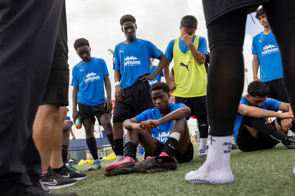 Moises Badera, bottom center, and his teammates sit in their emotions as they listen to their coach talk after their lost on penalties at the regional final of the US Youth Soccer Presidents Cup, on June 14, 2026, in Round Rock. (Antranik Tavitian for The Texas Tribune)