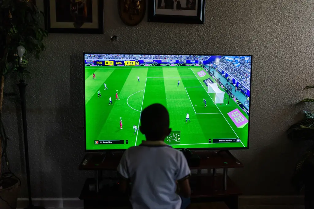 Rene Ngongo plays FC26, a soccer video game, as he and Moises’s family wait to watch a World Cup match, Sunday, June 21, 2026, in Houston. (Antranik Tavitian for The Texas Tribune)