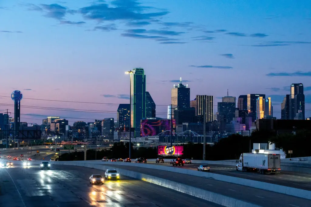 Cars drive on Interstate 35 East with the downtown Dallas skyline in the distance on July 27, 2025.
