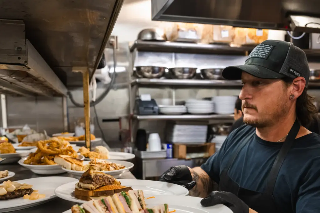 Line cook David Norton passes food to the servers during a lunchtime rush at George’s Restaurant in Waco, TX on June 25, 2026.